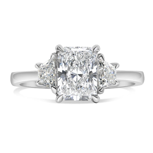 14K white gold three stone ring featuring a 1.5 carat lab grown radiant cut center diamond with trapezoid side diamonds.