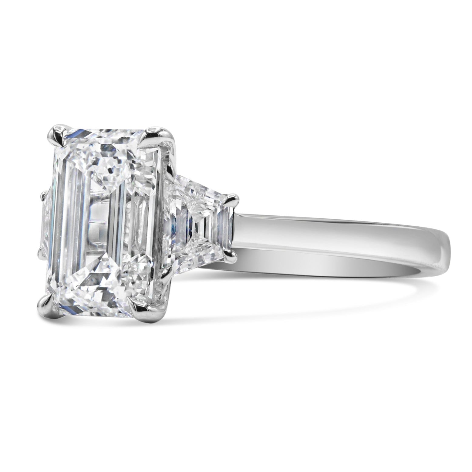 Emerald and step cut trapezoid three stone diamond ring in 14K white gold featuring a lab grown emerald cut center diamond with step cut trapezoid side stones.