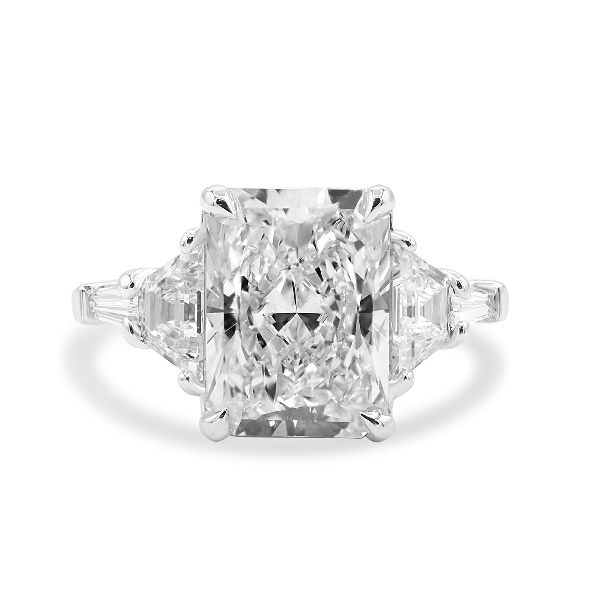 Platinum five-stone ring featuring a 3.66 carat radiant cut center diamond flanked by step-cut trapezoid and tapered baguette diamonds.